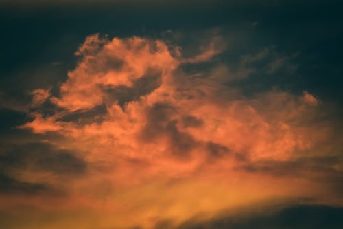 Free Low angle of spectacular vivid orange clouds floating in gray dramatic sunset sky Stock Photo