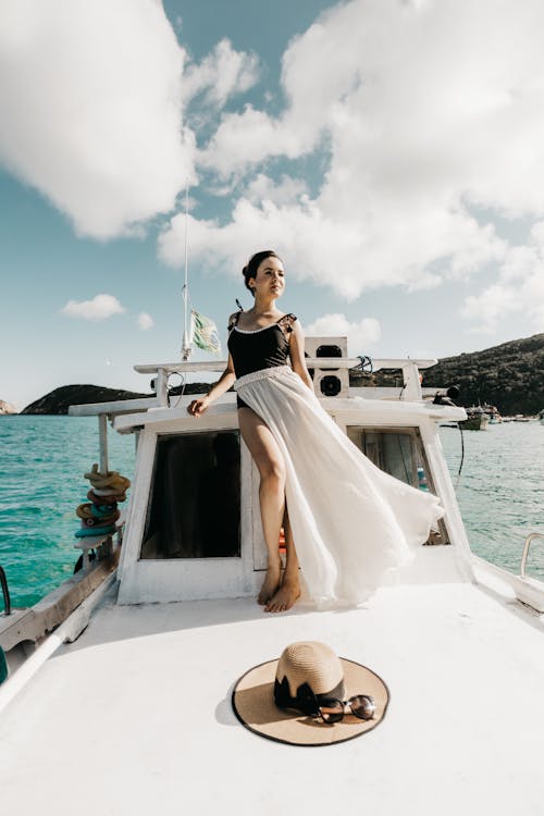 Low angle full body of relaxed young female standing on yacht sailing on blue sea