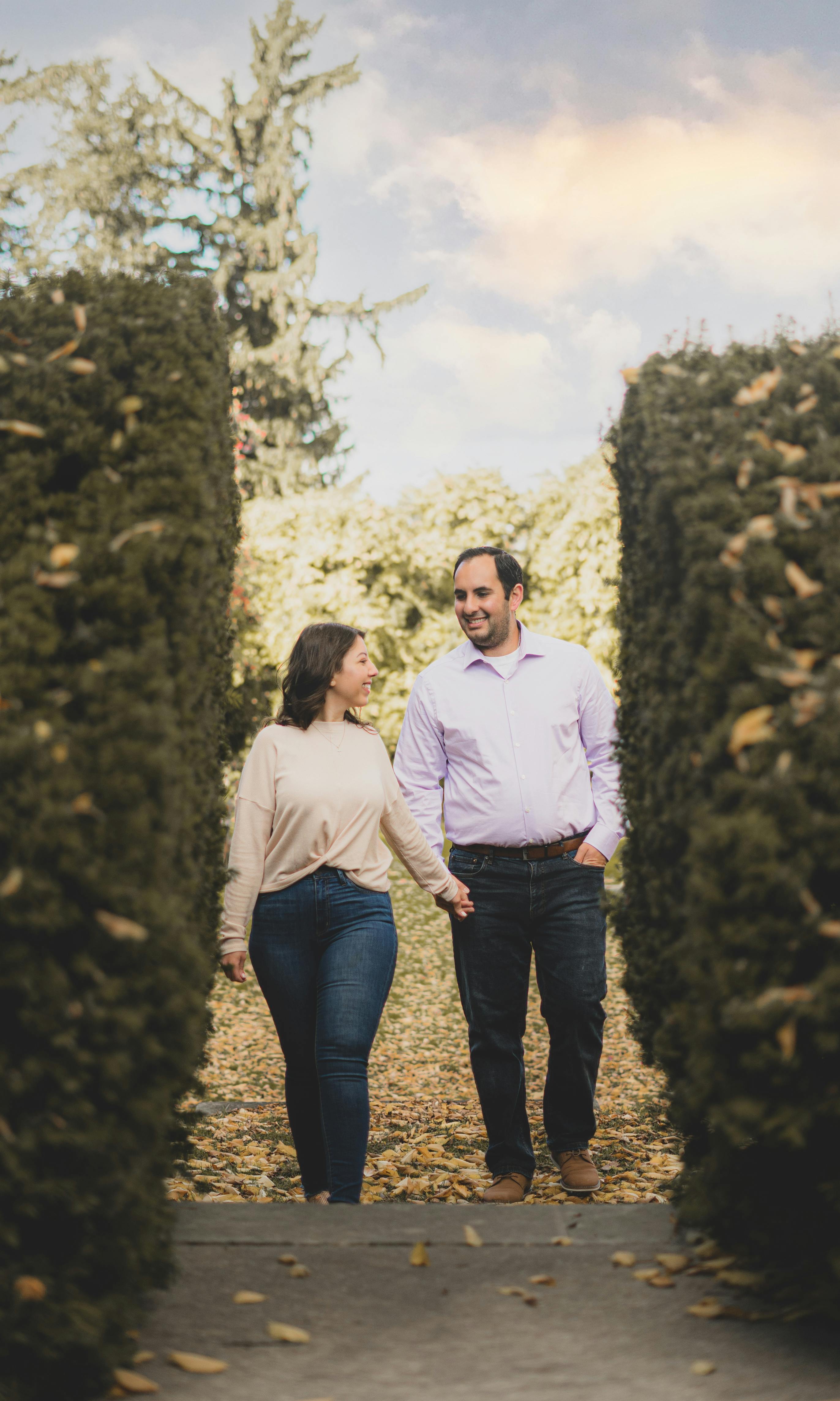 cheerful couple walking among green bushes in park