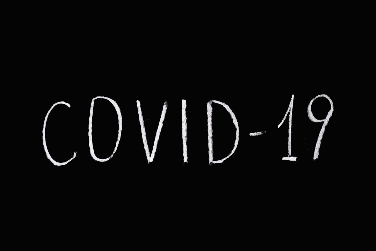 white chalked covid 19 text on a blackboard background emphasizing pan