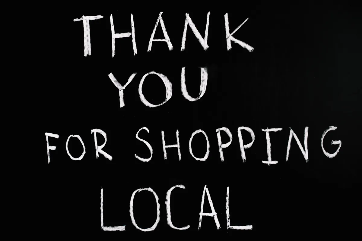 "Thank you for shopping local" written in white chalk on black background
