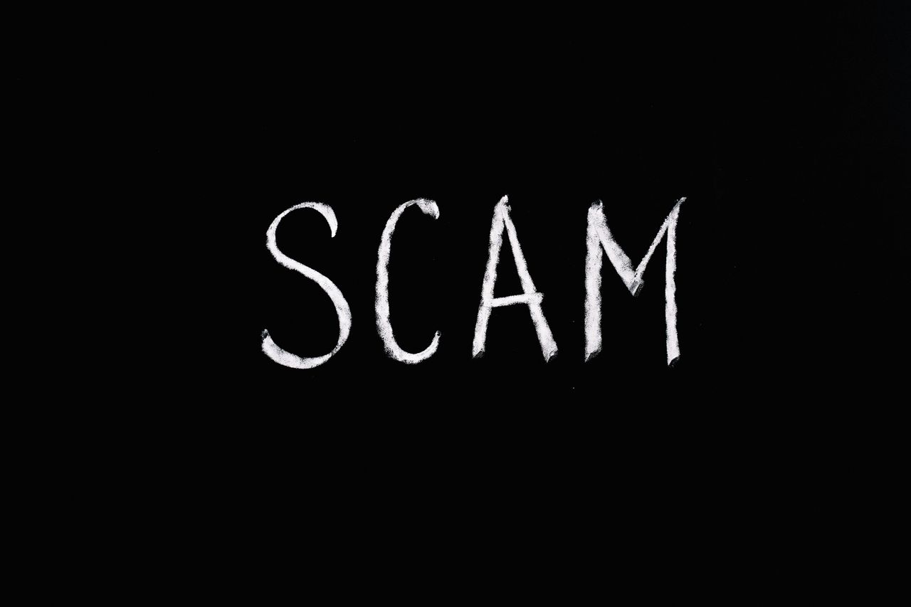 chalk drawn text scam on black background representing fraud and decep