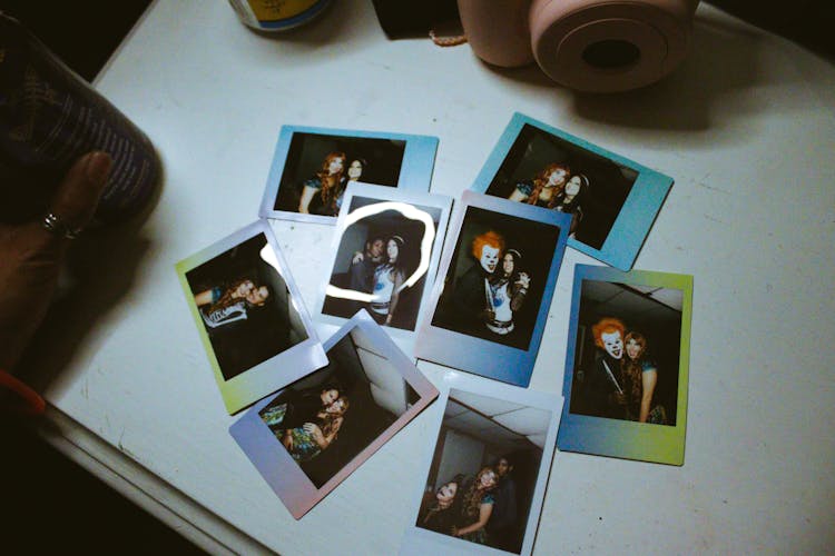 Instant Photos Of Girlfriends Near Photo Camera On Table