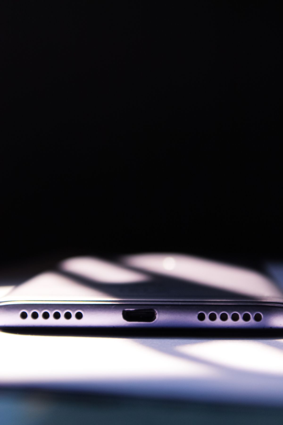 Close-up of a smartphone charging port with dramatic shadows