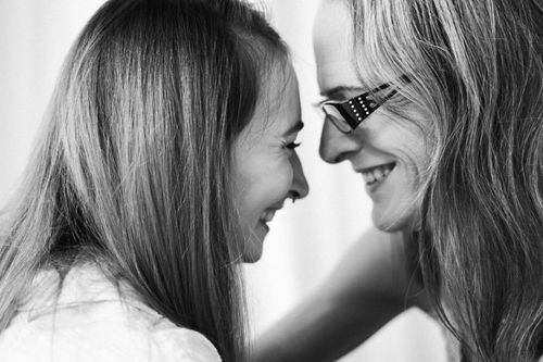 Free Black and white close-up portrait of two smiling women with long hair embracing a tender moment. Stock Photo