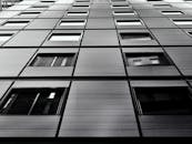 低角度镜头拍摄的黑白现代摩天大楼立面，带有几何窗户