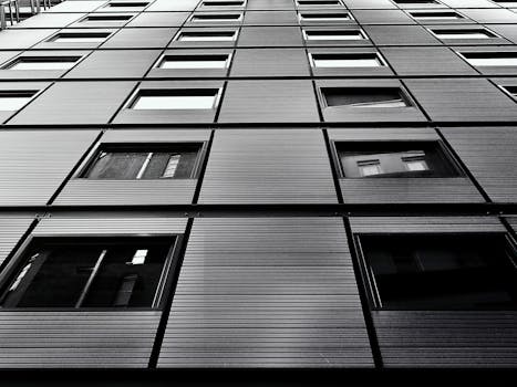 低角度镜头拍摄的黑白现代摩天大楼立面，带有几何窗户