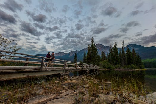 A couple enjoys a tranquil moment on a wooden bridge at Pyramid Lake in Jasper National Park, Alberta, Canada.