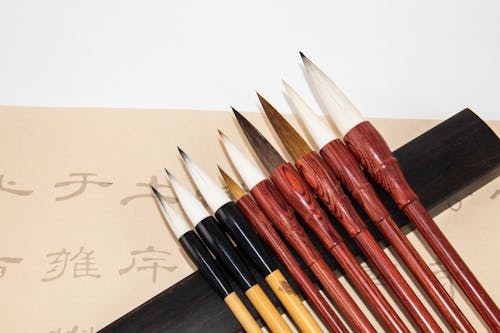 Set of calligraphy brushes near paper with hieroglyphs