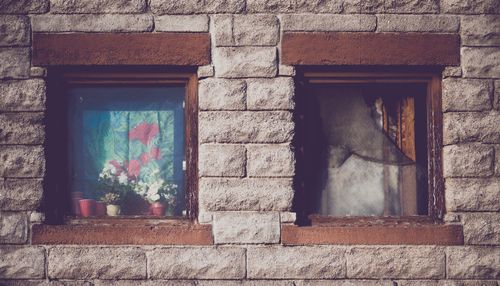 Free Exterior of aged stone building with small windows with potted plants in sunny day Stock Photo