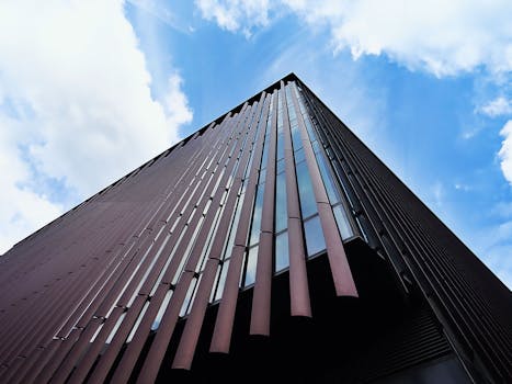 低角度视角下的现代摩天大楼，映衬着明亮的蓝天与云层