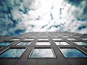 低角度的现代摩天大楼在玻璃窗中映出壮观的云层与天空