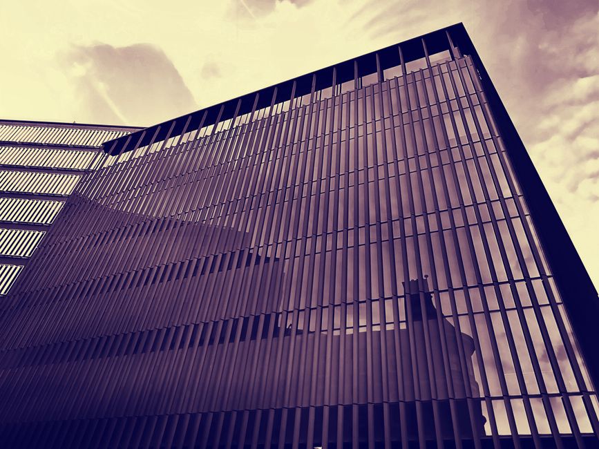 Vista en ángulo bajo de un rascacielos moderno con fachada de vidrio reflectante y líneas arquitectónicas dinámicas.