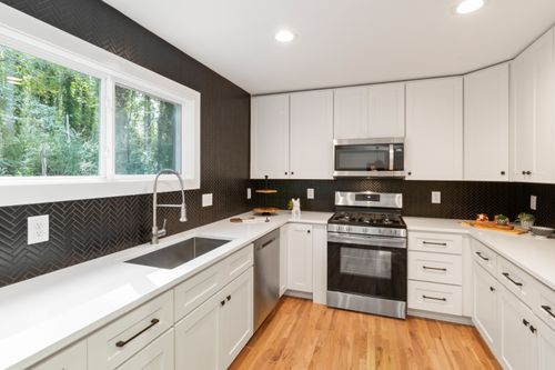 Free Stylish modern kitchen featuring white cabinets, stainless steel appliances, and wooden flooring. Stock Photo