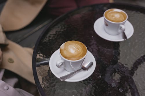Free Cups of Coffee on Saucers over a Round Glass Table Stock Photo