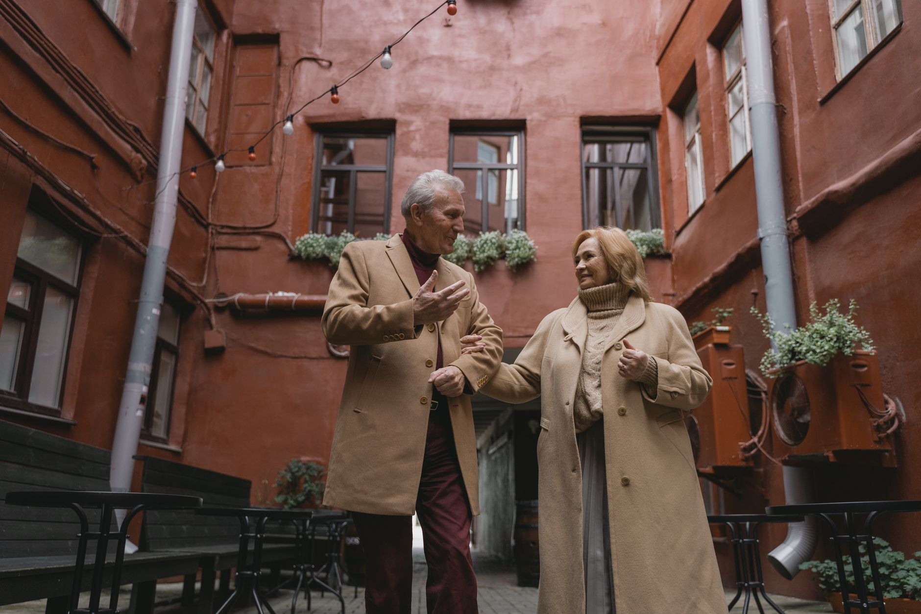 A joyous elderly couple walking hand in hand, sharing a moment in an urban setting.