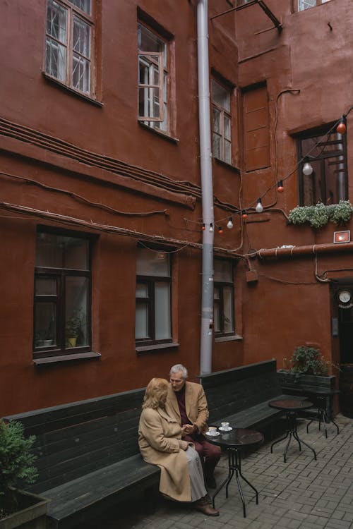 Couple Sitting on a Bench beside a Building