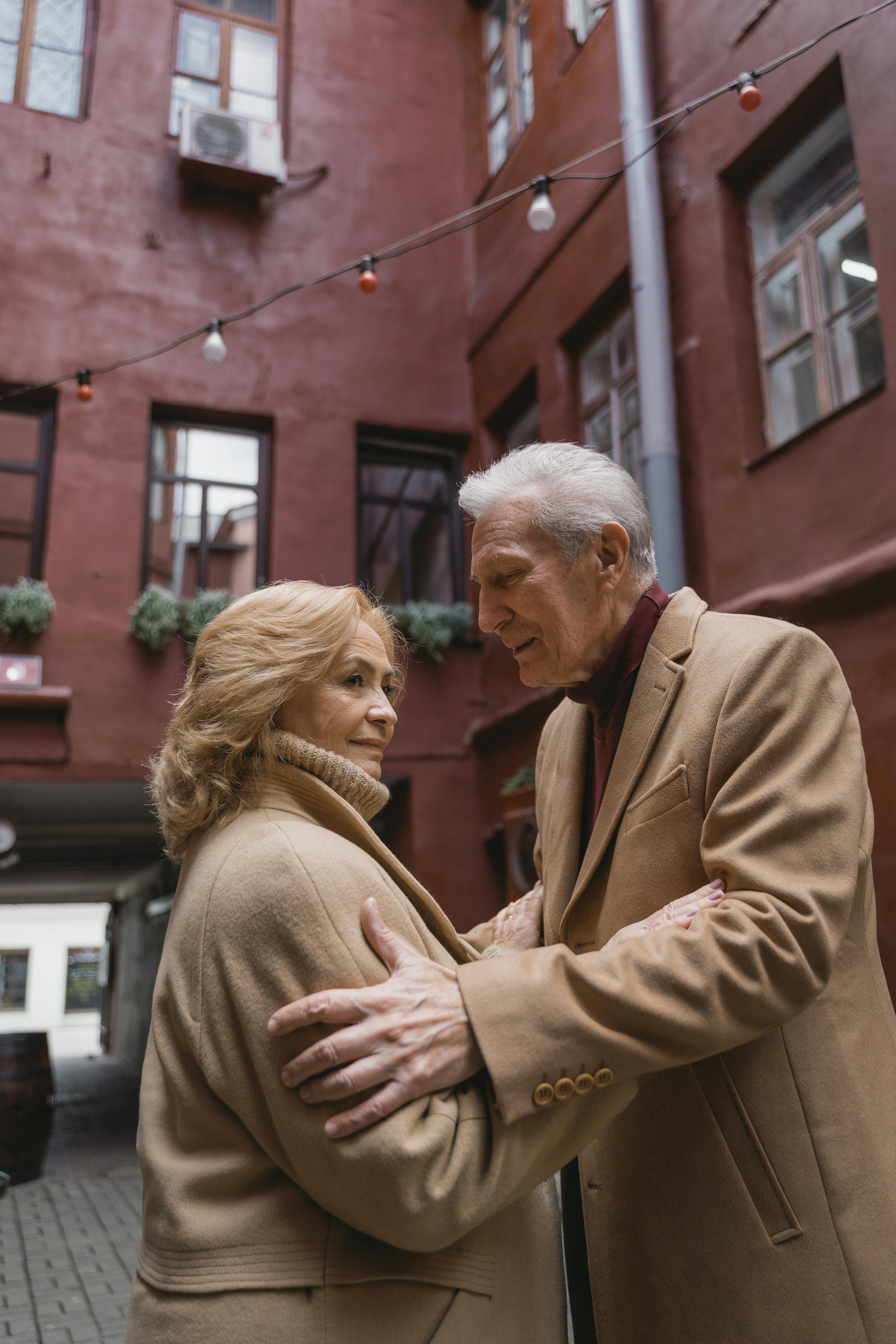 An elderly couple sharing an affectionate moment in a charming urban courtyard.