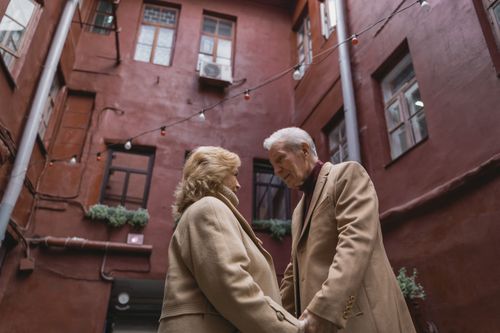 Free Senior couple holding hands in cozy courtyard, expressing love and warmth. Stock Photo