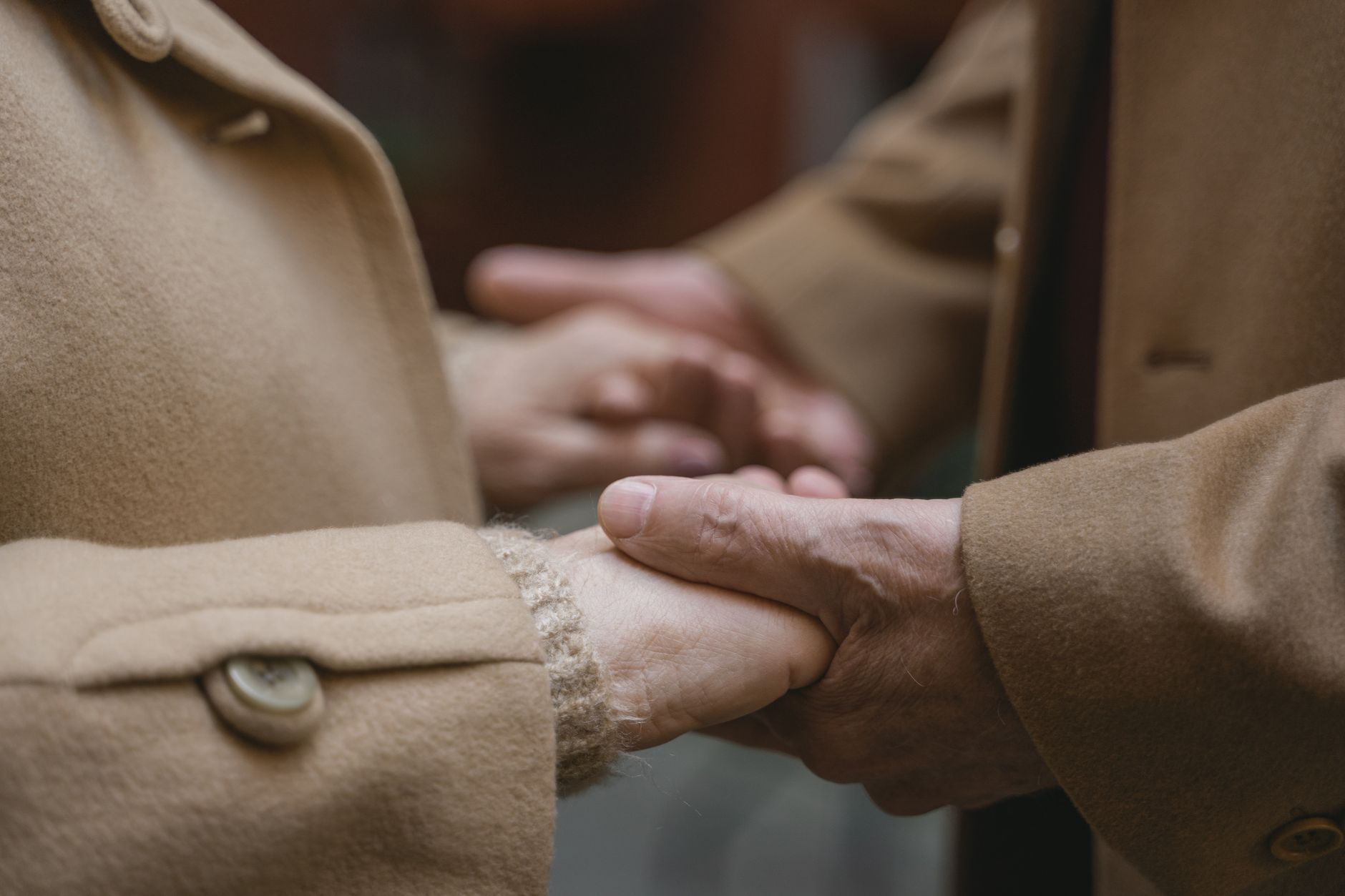 Intimate moment of two people holding hands in warm coats, illustrating connection and warmth.