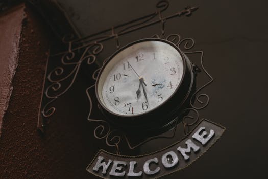 A nostalgic vintage clock with a welcoming sign captured in a low angle shot.