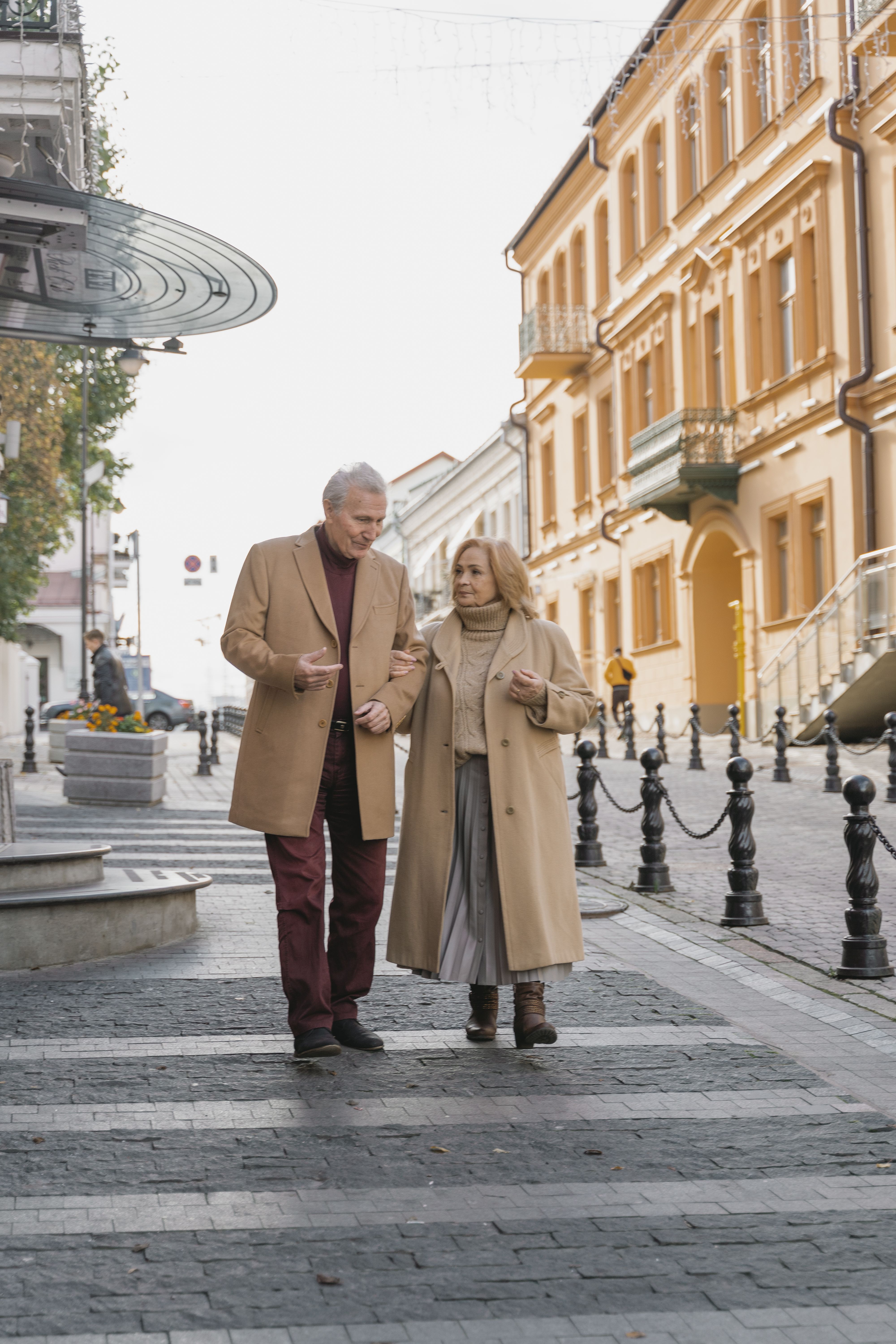 Affectionate senior couple walking together on a charming city street in fall.