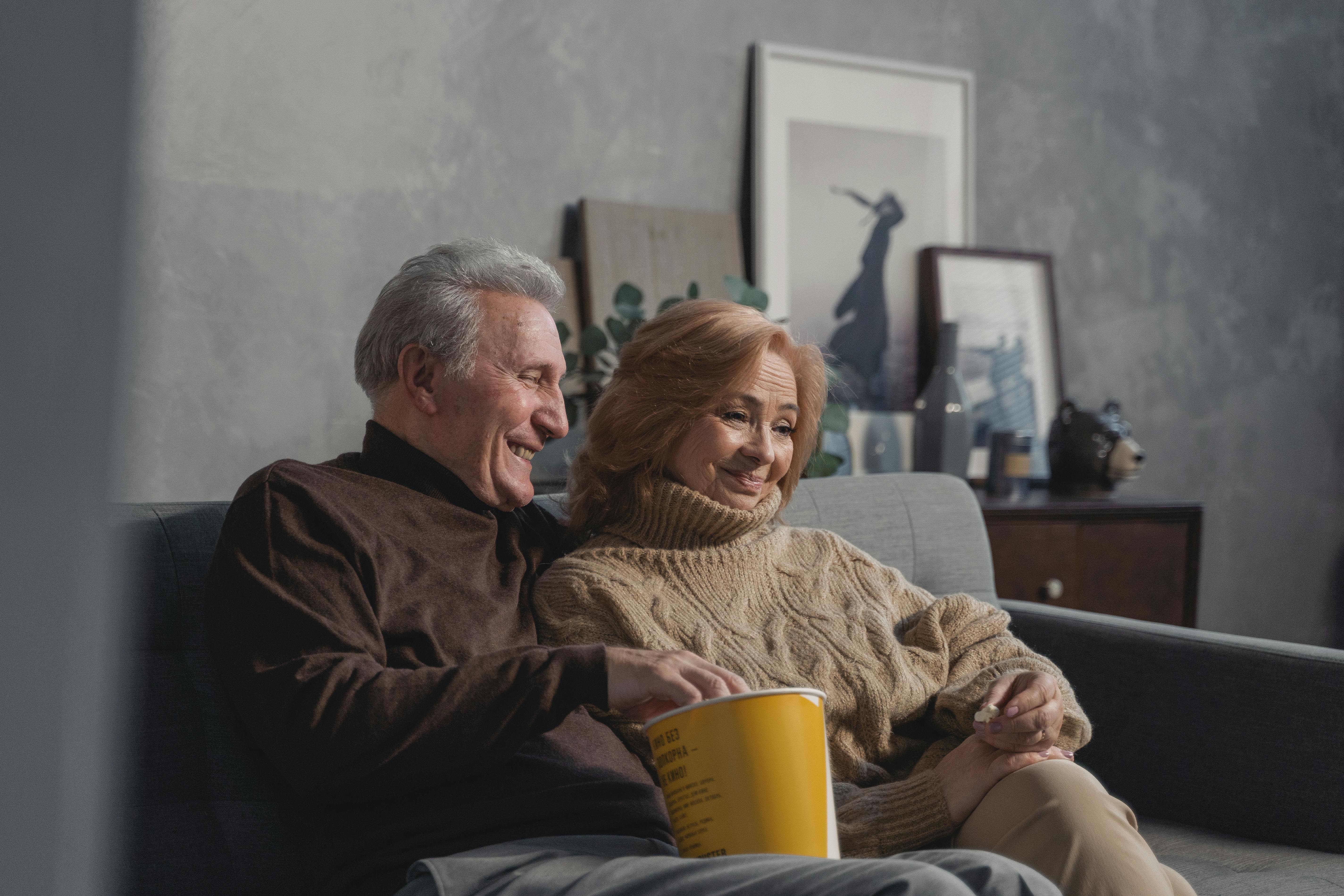 A senior couple enjoying a cozy moment on the couch, illustrating love and companionship.