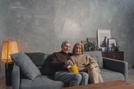 一对高级夫妇在温暖的客厅里，舒适地坐在沙发上一起享用爆米花