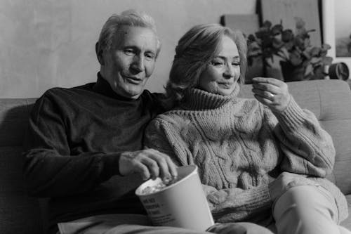 Couple Eating Popcorn Together while Sitting on a Sofa