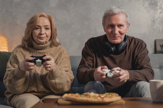 Senior couple playing video games together with pizza on the table, enjoying leisure time at home.