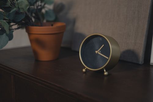 Free Stylish minimalist clock and potted plant on wooden table, perfect for decor inspiration. Stock Photo