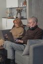 Man and Woman Sitting on Couch Using Macbook