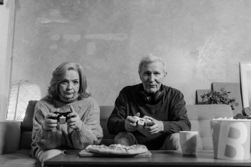 Free Senior couple playing video games on the couch, sharing a moment of fun and relaxation. Stock Photo