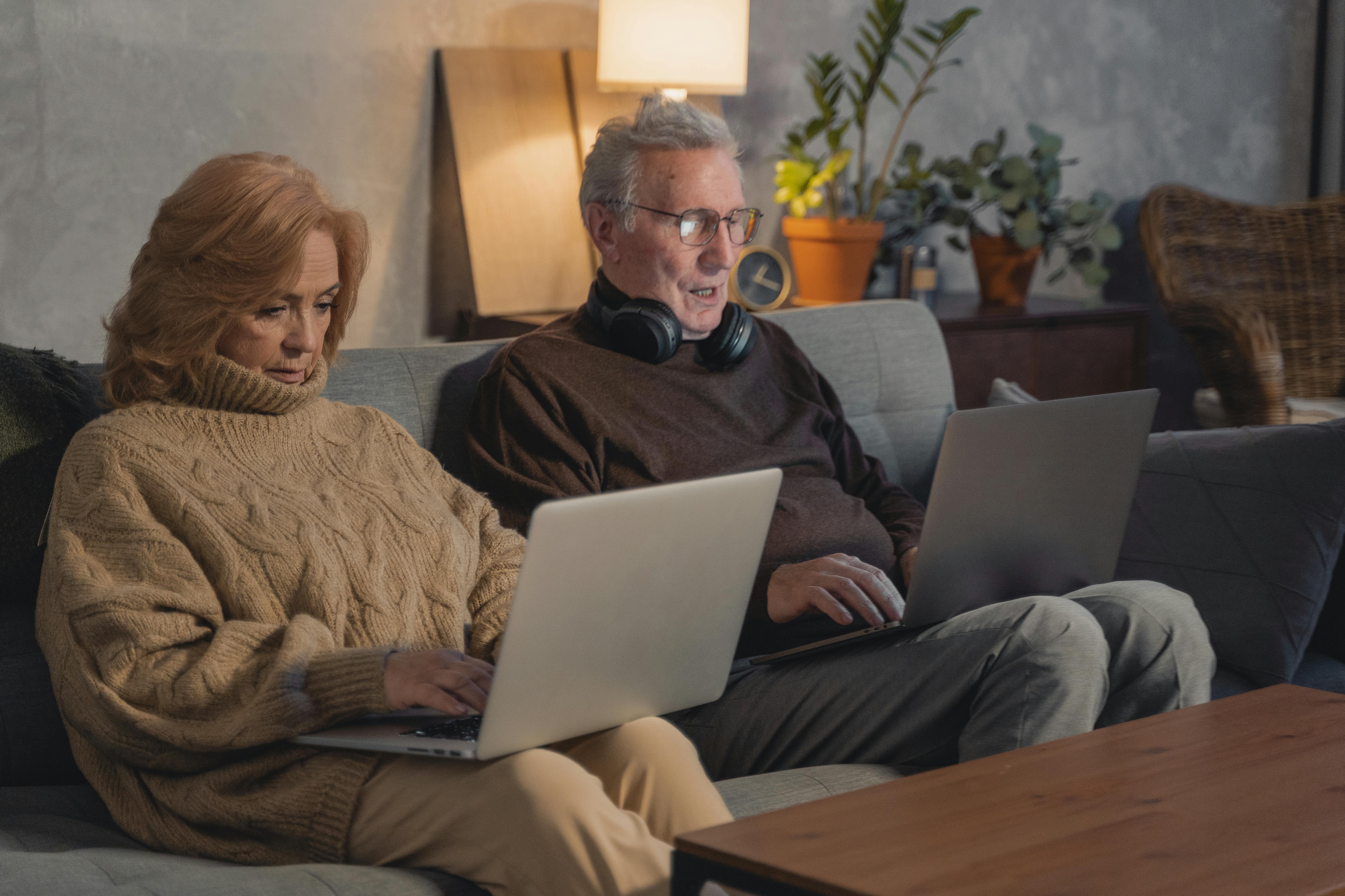 man and woman sitting on couch using macbook