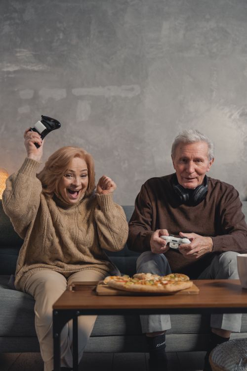 Free Happy senior couple playing video games together, celebrating a win. Stock Photo