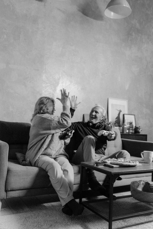 Free Senior couple enjoying video games together on the sofa at home, having fun. Stock Photo