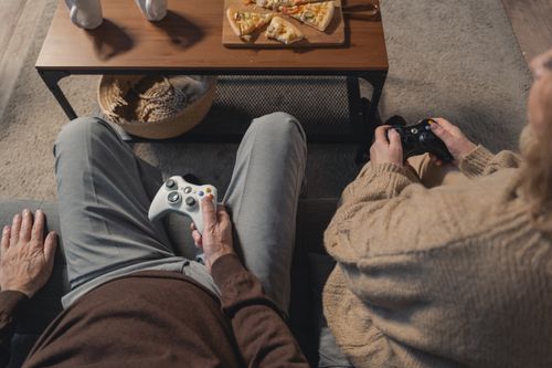 Free Elderly couple playing video games on the sofa, enjoying leisure time with a console. Stock Photo