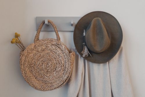 Free A rustic woven bag and hat hanging on a peg, showcasing minimalist interior decor. Stock Photo