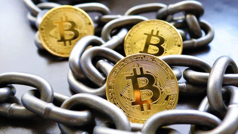 Close-up of Bitcoin coins entwined in metallic chains showcasing cryptocurrency security.