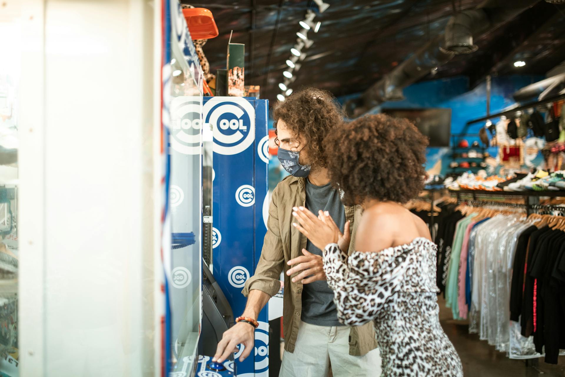 A couple wearing masks using an ATM in an urban clothing store.