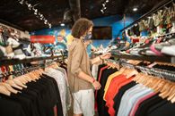 一个时髦的年轻人在时尚的城市商店里戴着面具买衣服