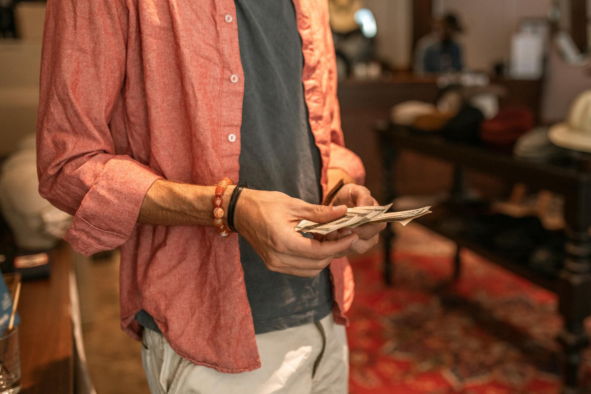 A person in a casual outfit counting money inside a boutique store.