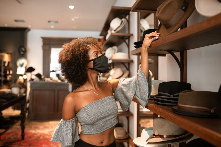 Woman Wearing Face Mask Shopping For A Hat