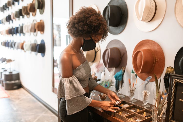 Woman Holding An Object Near Hats Hanging On A Wall