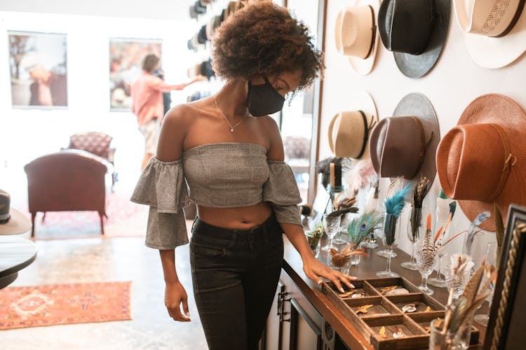 Woman In Gray Top And Black Pants Looking At Items In A Shop