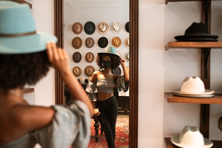 A Woman Wearing A Hat Looking In The Mirror