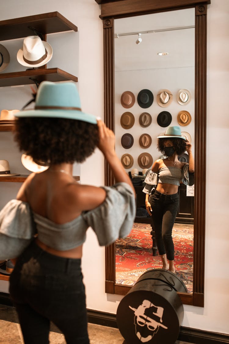 A Woman Wearing A Hat Looking In The Mirror