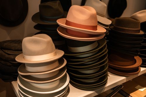 Free A collection of fashionable fedora hats neatly stacked in a boutique setting, showcasing elegance and style. Stock Photo