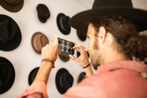 Close-Up Shot of a Person Taking Photos of Hats 