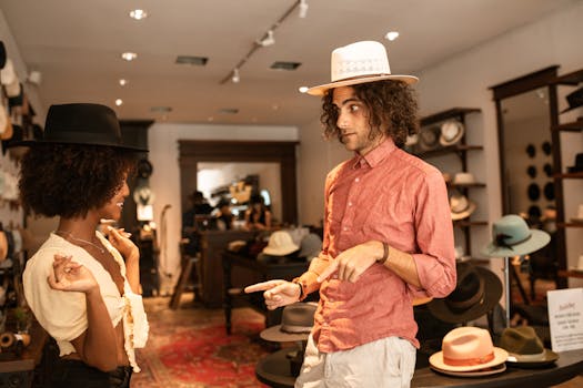 A young interracial couple enjoys trying on fashionable hats at a boutique shop.